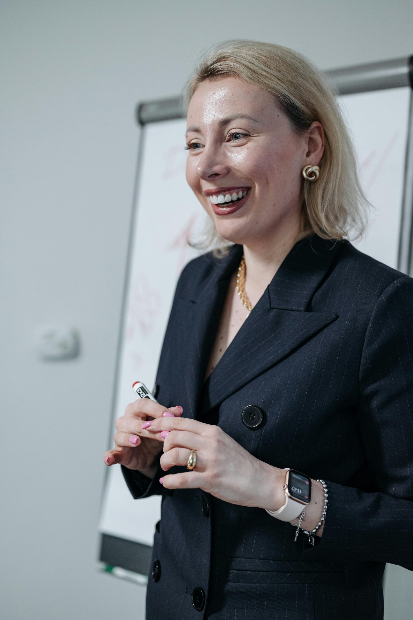 Smiling businesswoman in a suit presenting at a meeting, conveying leadership and confidence.